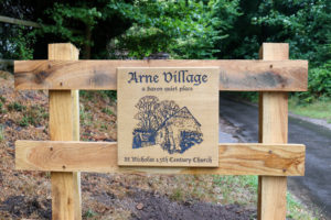 Arne village and St Nicholas church wooden sign