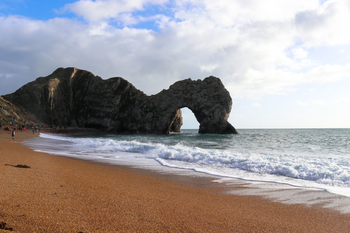 Durdle Door arch and beach with people walking