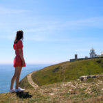 Girl in red dress looking over hills toward Anvil Point lighthouse