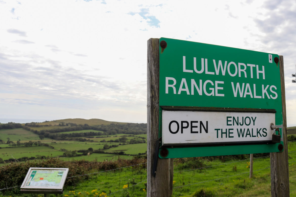 Lulworth Range walks sign with Purbeck hills in distance