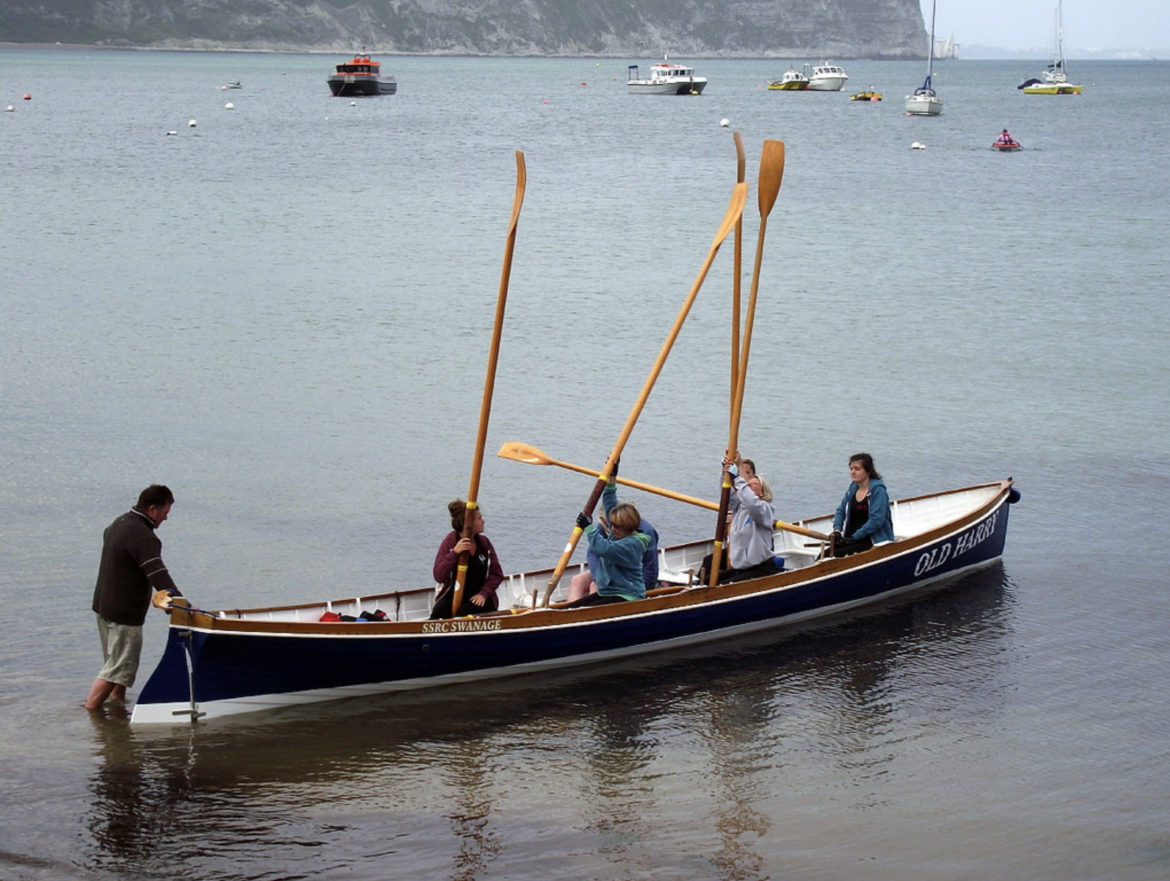 People in sea rowing boat in the sea at Swanage Beach