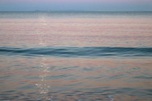 Pink sunset on the water at Swanage Beach with the Isle of Wight on the horizon