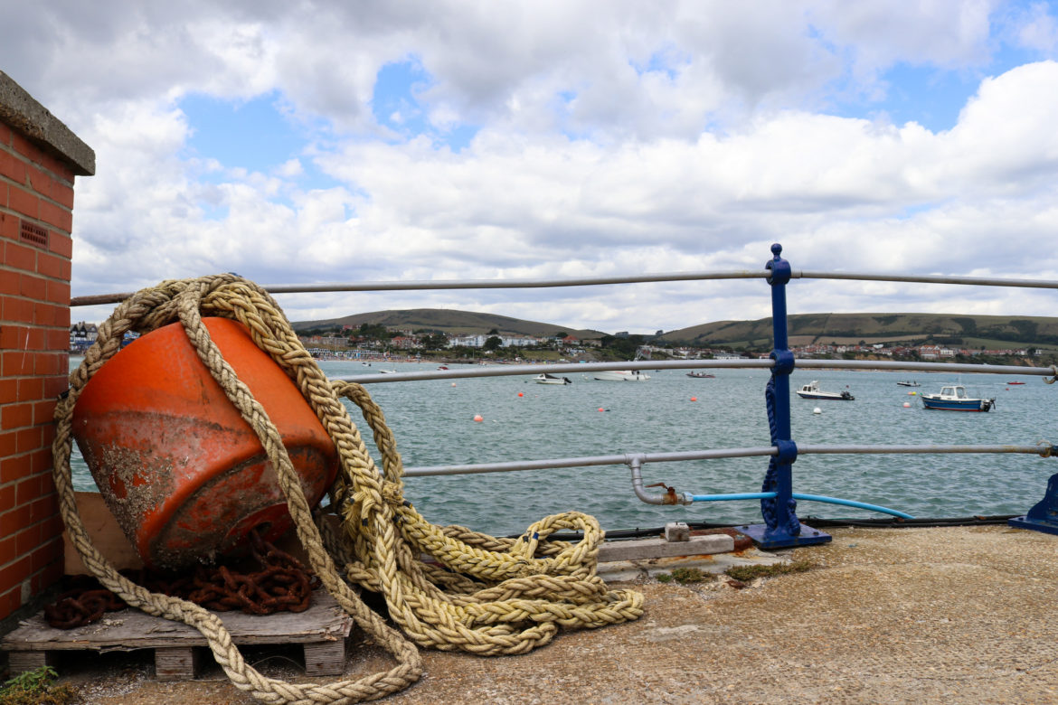 Rope and buoy on Swanage Pier with view of Purbeck Hills
