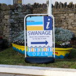 Swanage Information Centre sign in front of yellow boat planter