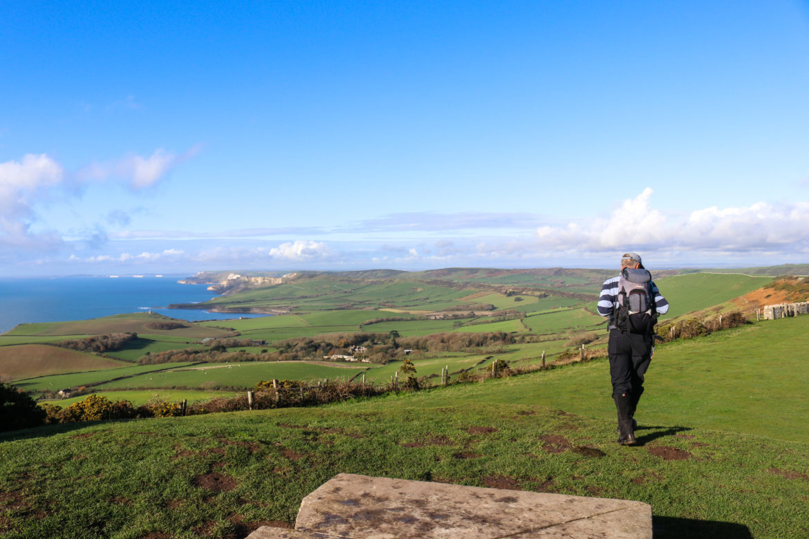 Man with backpack walking down the tumulus of Swyre Head