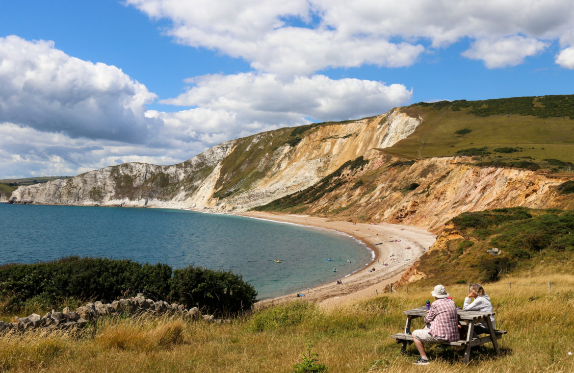 Couple sitting at a picnic table overlooking Worbarrow Bay
