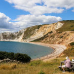 Couple sitting at a picnic table overlooking Worbarrow Bay