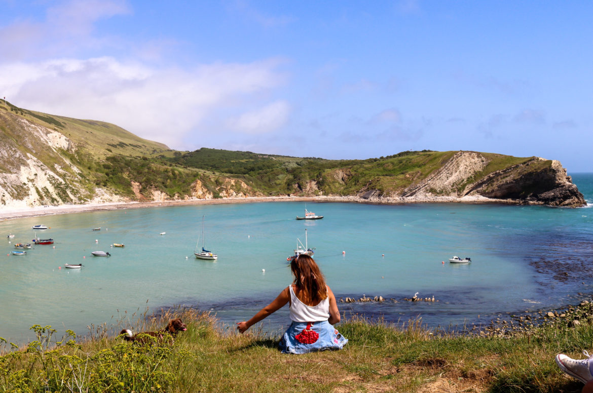 Girl and dog sitting above Lulworth Cove