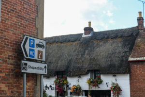 Parking and toilet sign in Wareham with thatched pub behind