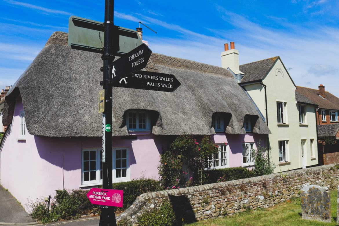 Pink thatched cottage and road signs in Wareham