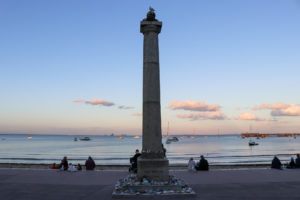 People sitting on the promenade by the King Alfred memorial in Swanage
