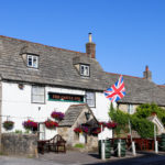 British flag and hanging baskets outside the Castle Inn pub in Corfe Castle