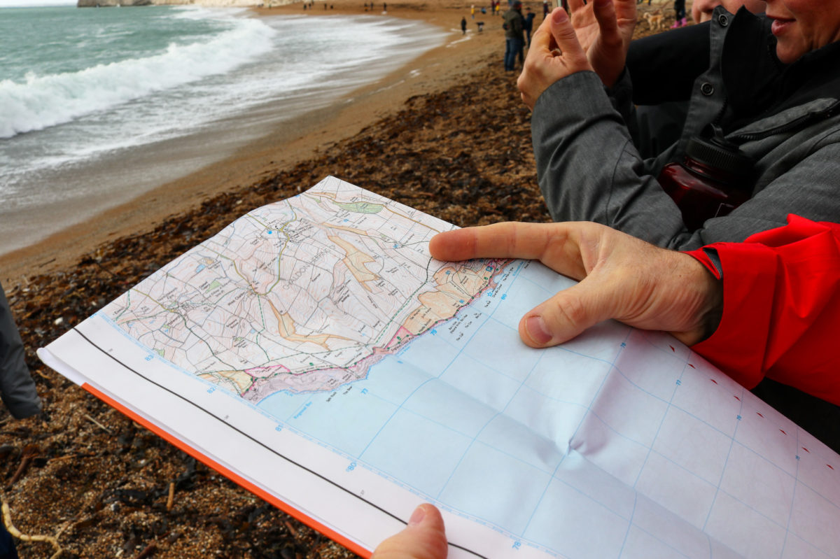 Person looking at map on Durdle Door beach