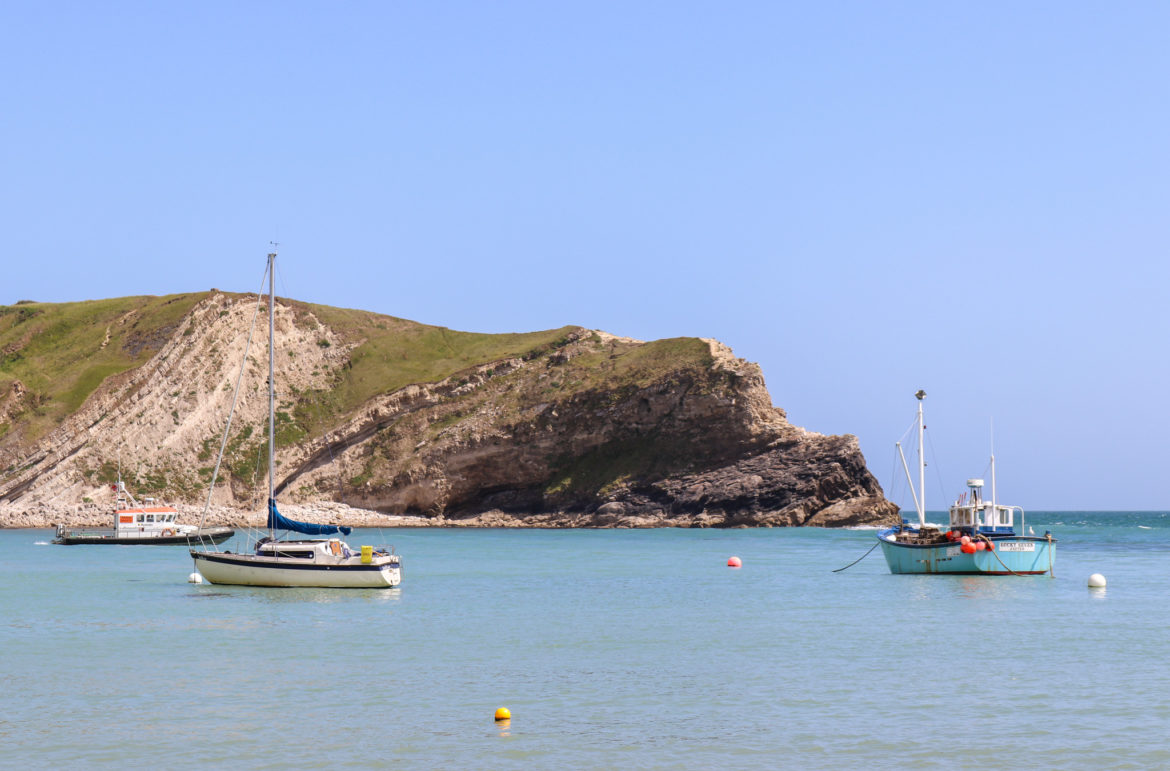 Fishing boats in the cove at Lulworth with strata in cliff behind