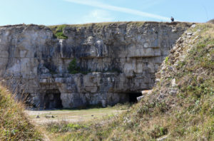 Person walking on the cliff above caves at Winspit