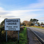 Sign on the road at the entrance to Harman's Cross village