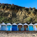 Striped beach huts in front of the cliff at Swanage Beach
