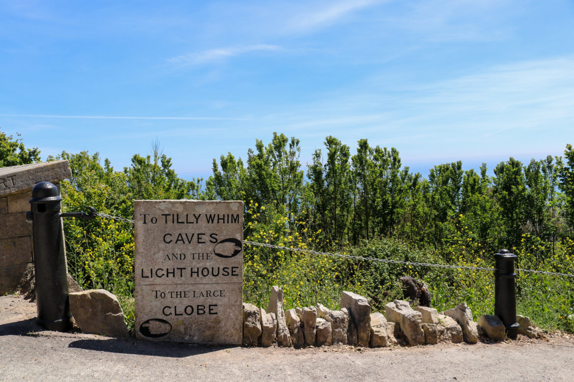 Stone sign for the Tilly Whim Caves, lighthouse and globe at Durlston Country Park