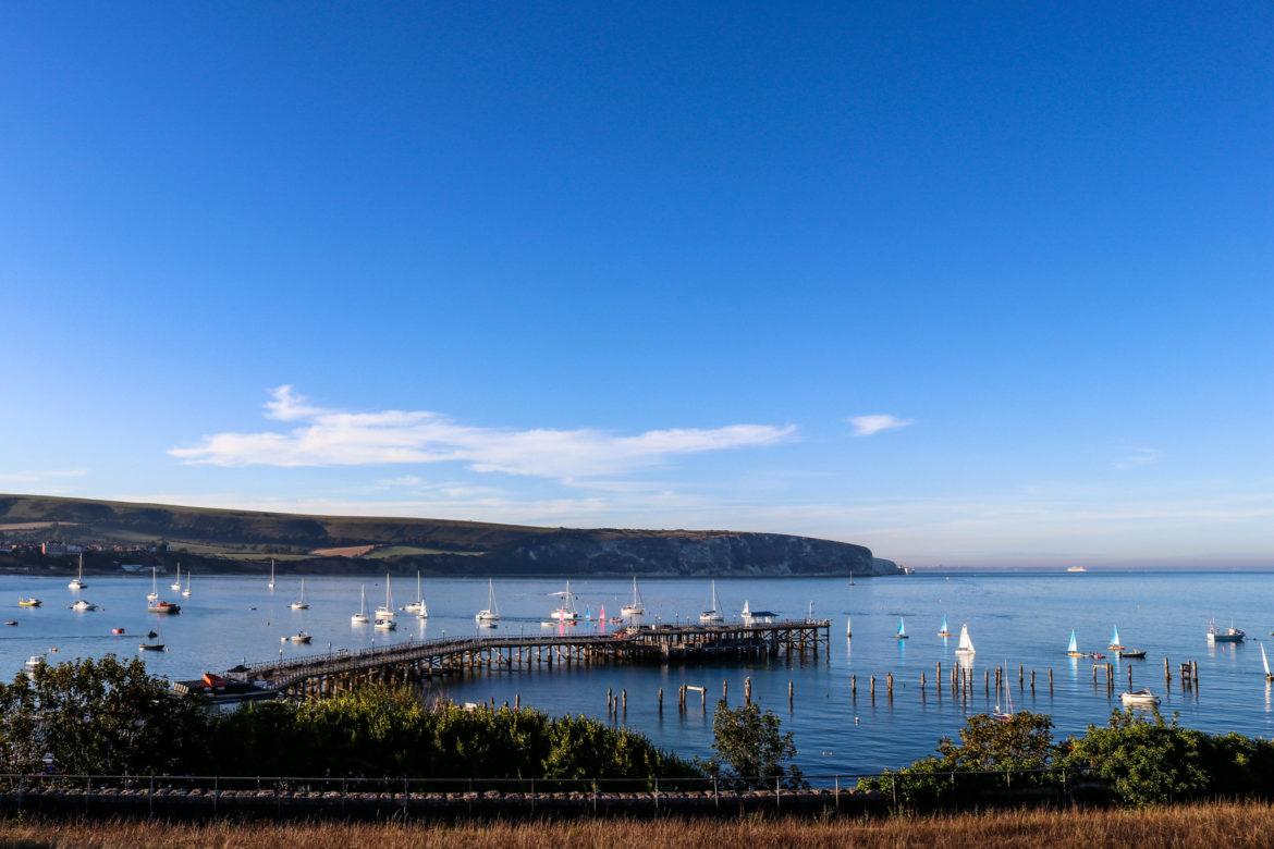 Both new and old piers in Swanage, with sailing boats in the bay