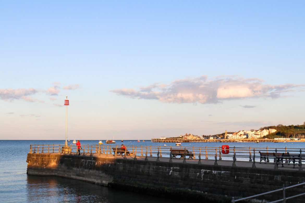 Sun setting on banjo pier and Swanage Pier across the bay
