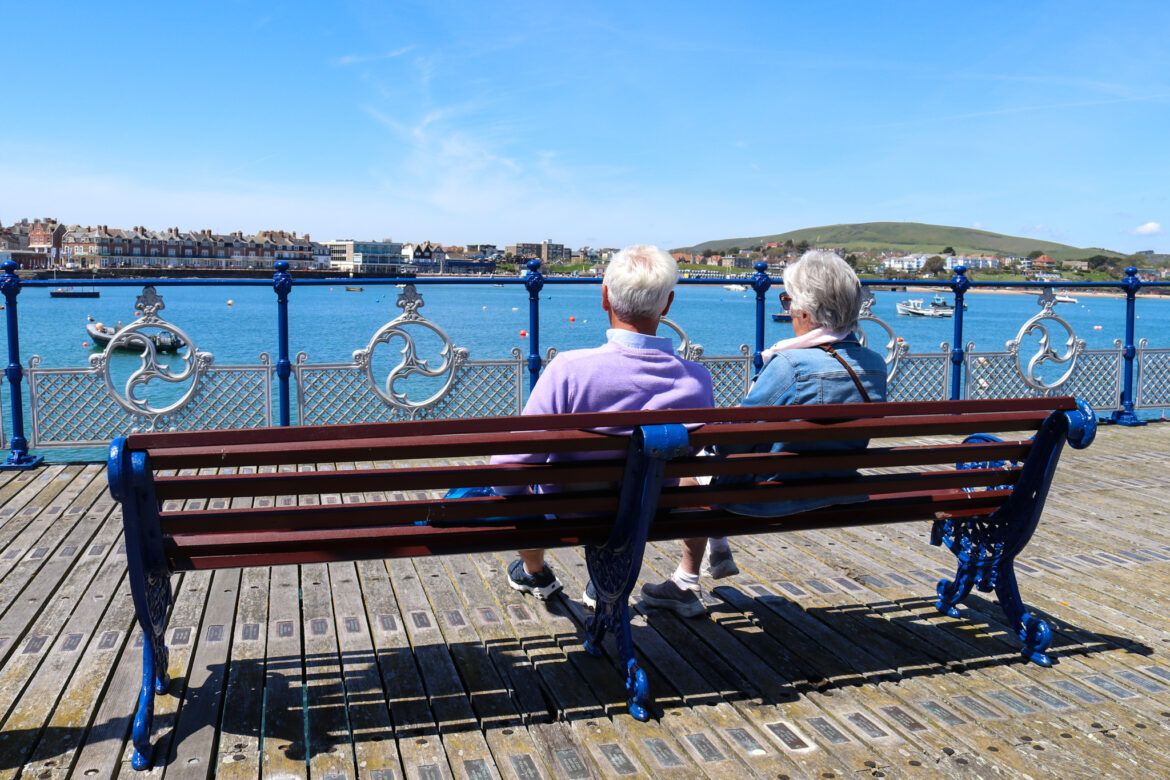 A couple sitting on a bench of Swanage Pier looking at the view