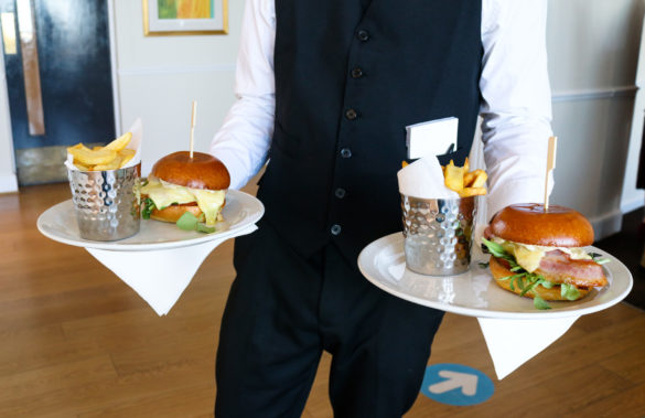 Waiter holding two plates of brie and bacon burgers at the Grand Hotel, Swanage