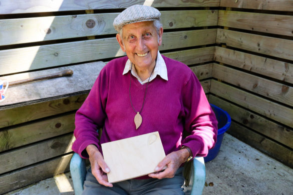 Man holding whittled work of leaf and mouse cheese board at Durlston Country Park