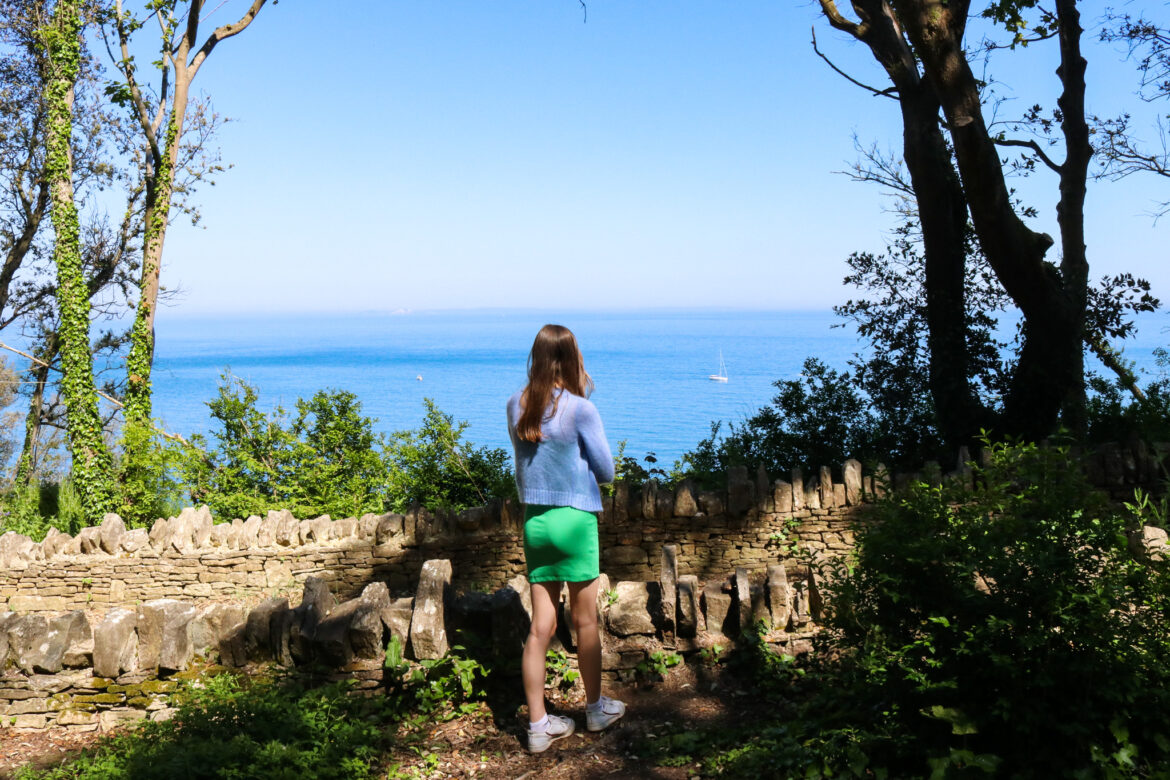 Girl looking at sea from woodland path in Durlston