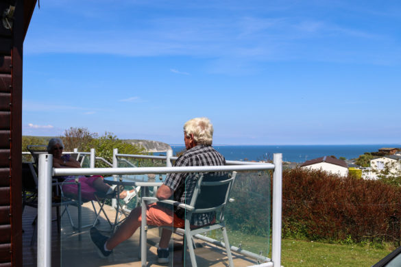 People sitting on the deck of a holiday home at Swanage Coastal Park