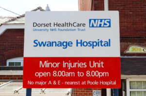 Welcome board and opening hours information outside Swanage Hospital Minor Injuries Unit