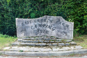 Carved wooden welcome sign for East Creech Farm Camping Site