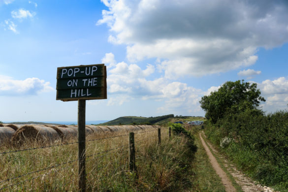 Pop-Up on the Hill sign with Dorset Coast and sea in the distance