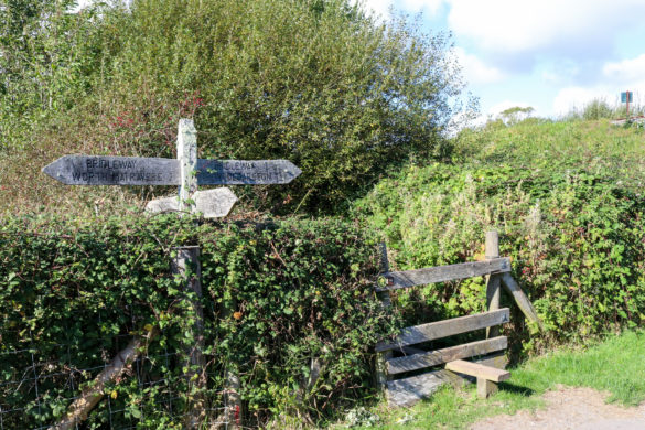 Path with stile and wooden signposts at a walking path near Woodyhyde Campsite