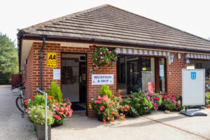 Flowers and five pennant AA award sign outside the Reception and shop building at the Wareham Forest Tourist Park