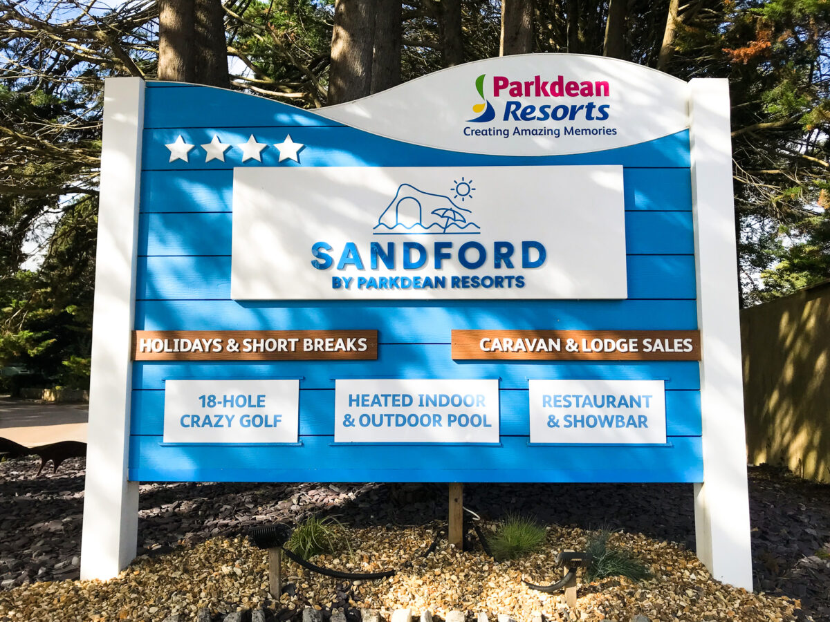 Sign outside Parked Resort Sandford showcasing its 18-hole gold course and indoor & outdoor swimming pools