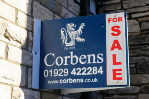 For Sale sign by Corbens Swanage attached to brick wall